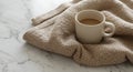 A white ceramic mug filled with coffee rests on a beige knitted sweater. The Royalty Free Stock Photo