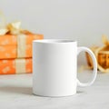White ceramic mug with handle in front of stacked orange gifts with ribbons on a marble surface top Royalty Free Stock Photo