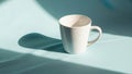 White ceramic mug on a light blue surface casting a soft shadow Royalty Free Stock Photo