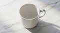 White ceramic mug on a marble surface. The mug is simple, with a round shape and Royalty Free Stock Photo