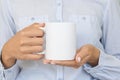 White ceramic mug mockup. Girl wears blue shirt Holds a Cup of cocoa. Space for your text branding