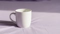Ceramic mug with a rounded handle sits on a smooth light lavender Royalty Free Stock Photo