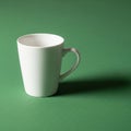 A white ceramic mug sits on a green textured surface, casting a shadow to the Royalty Free Stock Photo