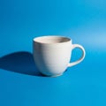 White ceramic mug with a smooth glossy surface on a bright blue backgroun Royalty Free Stock Photo