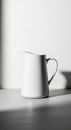 White ceramic pitcher with a smooth, glossy surface, positioned on a flat surface. Lig Royalty Free Stock Photo
