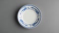 Ceramic plate with blue floral pattern along the rim set against a gray Royalty Free Stock Photo