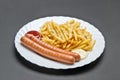 White ceramic plate with French fries, two grill sausages, ketchup and mayonnaise Royalty Free Stock Photo