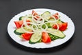 White ceramic plate with fresh cucumber, tomato and onion salad