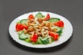 White ceramic plate with fresh tomatoes, cucumber, celery, lettuce and meat salad