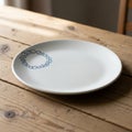 A white ceramic plate with a minimalist design of blue circular patterns rests on a rustic wooden Royalty Free Stock Photo