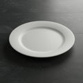 A white ceramic plate rests on a dark, textured tile surface. The plate is round with a Royalty Free Stock Photo