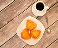 A white ceramic plate with three cottage cheese buns and a cup of black coffee on a wooden table Royalty Free Stock Photo