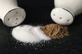 White ceramic salt and pepper shakers on black table, closeup