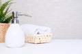 White ceramic soap dispenser, spa towel and green plan on white counter table inside a bright bathroom background with Royalty Free Stock Photo