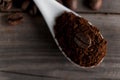 White ceramic spoon with ground coffee on a wooden background Fried Arabica grains Royalty Free Stock Photo