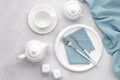 White ceramic tableware and cutlery. Utensils dishware, crockery, teapot and cup on gray marble background, table setting with Royalty Free Stock Photo