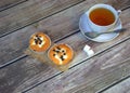 White ceramic tea cup on a saucer with a spoon and a napkin with two fresh muffins and cubes of sugar on a wooden table Royalty Free Stock Photo
