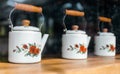 White ceramic tea pots with wooden handle, painted with red roses and displayed on a wooden shelf Royalty Free Stock Photo