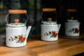 White ceramic tea pots with wooden handle, painted with red roses and displayed on a wooden shelf Royalty Free Stock Photo