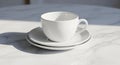 White ceramic teacup placed on stacked saucers, set on a smooth, white marble table. Royalty Free Stock Photo