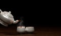 White ceramic teacup set On a wooden surface and a black background, pour the tea out of the pot onto the mug. 3D Rendering Royalty Free Stock Photo