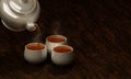 White ceramic teacup set On a wooden surface and a black background, pour the tea out of the pot onto the mug. 3D Rendering Royalty Free Stock Photo