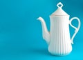 White ceramic teapot on blue background, copy space. Royalty Free Stock Photo