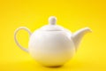 White ceramic teapot, china pot or tea kettle isolated on yellow background Royalty Free Stock Photo