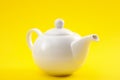 White ceramic teapot, china pot or tea kettle isolated on yellow background Royalty Free Stock Photo