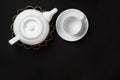White ceramic teapot and cup on a bamboo mat with clean black background