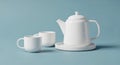 A white ceramic teapot with a lid and handle sits on a circular saucer alongside two Royalty Free Stock Photo