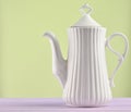 White ceramic teapot on a pastel purple wooden table isolated on Royalty Free Stock Photo