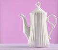 White ceramic teapot on a pastel purple wooden table isolated on Royalty Free Stock Photo