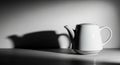 A white ceramic teapot sits on a flat surface, casting a large shadow on a plain wall. The teapot Royalty Free Stock Photo