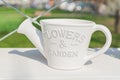 White ceramics flower pot in shape of watering can on the shelf outdoors, Garden or interior decoration