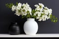 white ceramics vase with fresh flowers on a black shelf