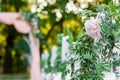 White chair decorated with pink rose and pistachio branches against the backdrop of a wedding arch Royalty Free Stock Photo