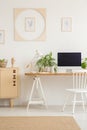 White chair at desk with desktop computer in workspace interior with plants. Real photo Royalty Free Stock Photo