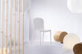 White chair on platform in bright showroom interior with big balloons and wooden blocks