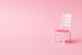 White chair with red seat on pink background