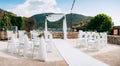 White chairs decorated with fabric stand in front of a wedding arch Royalty Free Stock Photo