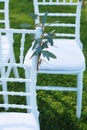 White Chairs Decorated with Ruscus Leaves at the Outdoor Wedding Ceremony Green Grass Background Party Celebrate Wedding Event Royalty Free Stock Photo