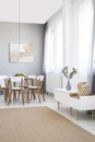 White chairs at dining table in scandi flat interior with cupboard, poster and carpet. Real photo Royalty Free Stock Photo