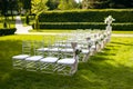 White chairs on a green lawn for a wedding ceremony are waiting for guests