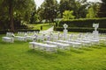 White chairs on a green lawn for a wedding ceremony are waiting for guests