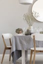 White chairs and laid table in an elegant and pastel dining room interior. Real photo Royalty Free Stock Photo