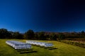 White chairs on a lawn with a dark polarized effect in the sky