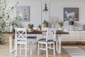 White chairs at table with flowers in rustic dining room interior with lamp and posters. Real photo Royalty Free Stock Photo