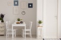 White chairs and table in minimal dining room interior with plants, posters and door. Real photo Royalty Free Stock Photo