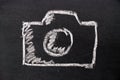 White chalk hand drawing as camera icon on black board